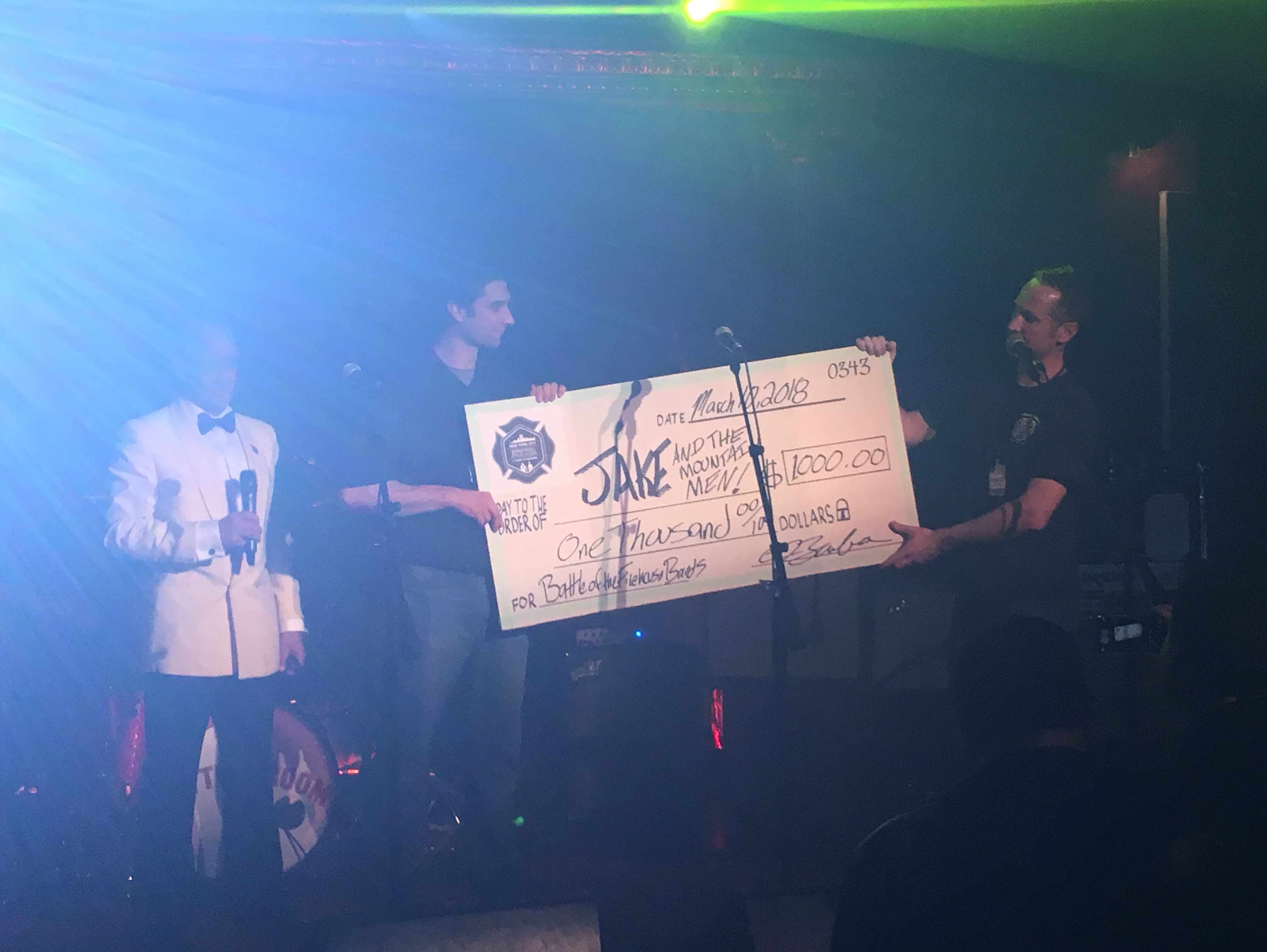 photo of Scott Hickey receiving a check for $1k for winning the Firehouse Battle Of The Bands with Jake And The Mountain Men